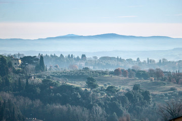 Fototapeta na wymiar Panorama of Tuscany mountains in morning winter fog, San Gimignano, Italy