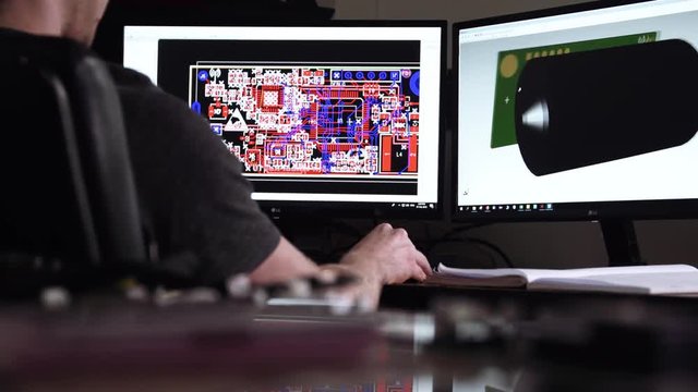 A research and development tech engineer uses a 3D CAD workstation to create and design high-tech electrical designs.