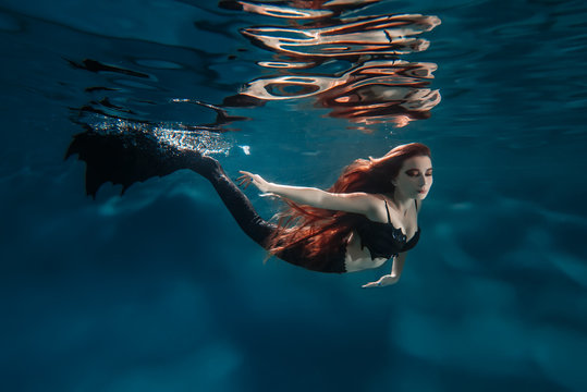 Underwater red hair freediver girl with mermaid tale
