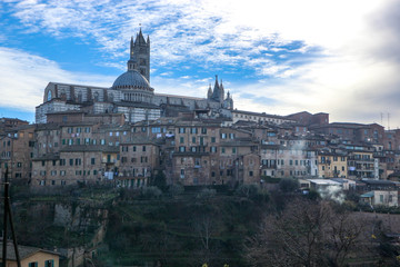 Fototapeta na wymiar Panorama of Siena old town and cathedral with bell tower in winter morning with blue sky and clouds on the background, Tuscany, Italy