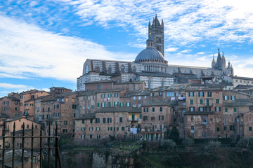 Fototapeta na wymiar Panoramic view of Siena old town and cathedral with bell tower in winter morning with blue sky and clouds on the background, Tuscany, Italy