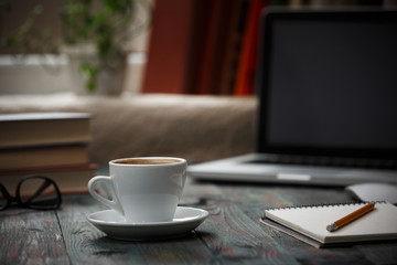 A cup of coffee in the workplace on a wooden table.
