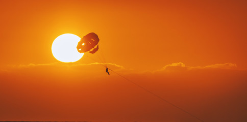amazing shot at sunset of Parasailing water amusement - flying on a parachute behind a boat on a summer holiday by the sea in the resort Baga beach Goa India