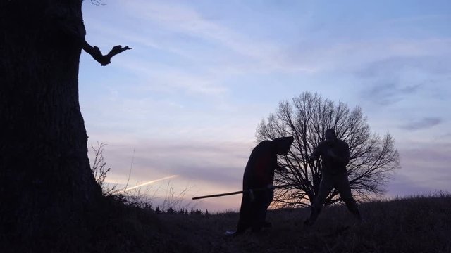 Grim Reaper fights with a man, a victim . sunset silhouette. concept of death and the struggle for life