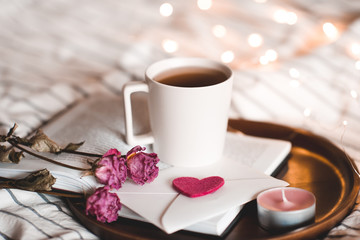 Cup of tea with flowers on open book closeup. Valentines Day. Bed time.