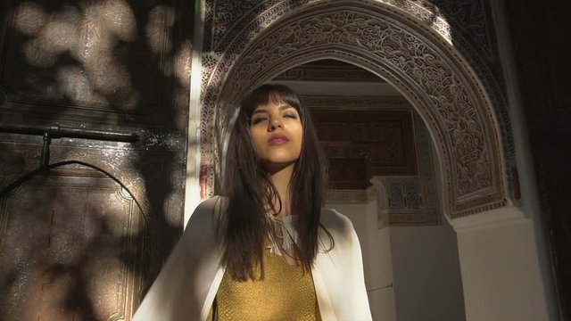 Beautiful Moroccan Girl Waving her white mantle in Picturesque Dar Si Said Riyad in Marrakech at sunset time