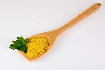 Raw vermicelli with parsley on a wooden spoon on a white background