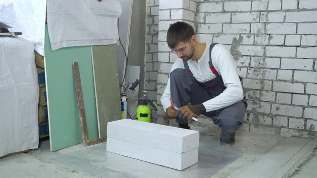 construction worker doing markup on aerated concrete block at construction site