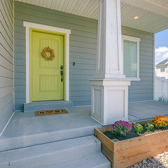 Yellow front door of a home with stairs and porch