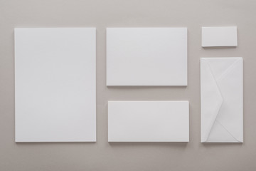 Fototapeta premium top view of empty papers and envelope with copy space on grey background