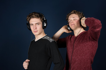 Two attractive guys listening to headphones.