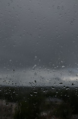 raindrops on glass against a gray sky