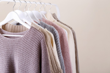 Warm knitted clothes hanging on a rack