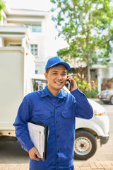 Smiling Vietnamese delivery service worker calling on phone