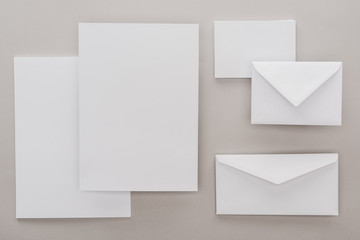 flat lay with white blank papers and envelopes on grey background