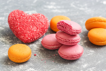 Yellow and pink macaroons with red sugar hearts. Selective focus.