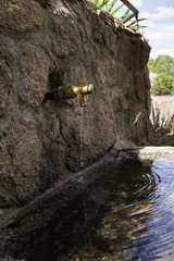Stone fountain with an iron spout with water running

