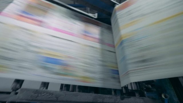 Coloured paper is moving through a printing machine at high speed
