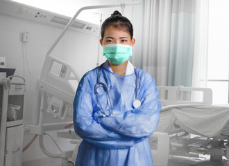 Fototapeta na wymiar confident and successful Asian Chinese medicine doctor woman in hospital scrubs and mask posing isolated at clinic patient bed in medical health care as corporate physician