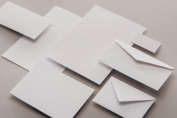 flat lay with blank white papers and envelopes on grey background - obrazy, fototapety, plakaty