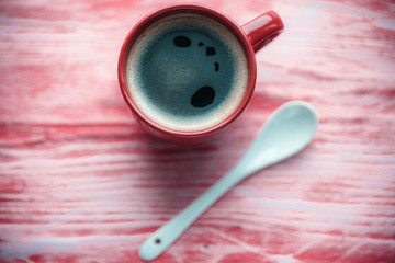 Red Cup with coffee on wooden background.