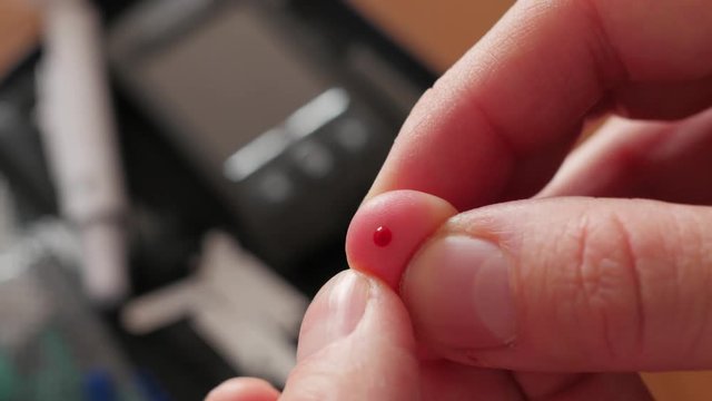 finger pricking to measure blood glucose, blood on finger