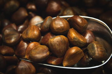 Hazelnuts with bark vegan together and accumulated being caught in the market with the metal shovel and woman's hand