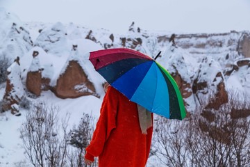 Beautiful landscape and winter in Cappadocia , Turkey .girl with colorful umbrella among the snow
