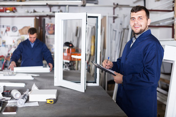smiling man surveyor in coverall  working with documents at workshop