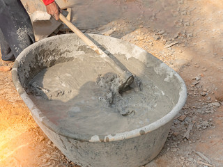 Mixing concrete by hands and spade in black basin