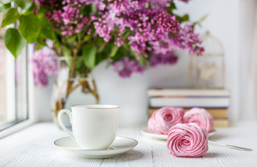 Bouquet of lilacs, cup of coffee, homemade marshmallow. Romantic spring morning. Selective focus