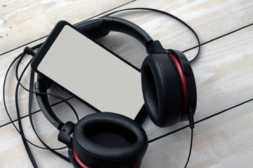 black headphones with smartphone on light wooden background
