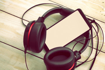 black headphones with smartphone on light wooden background