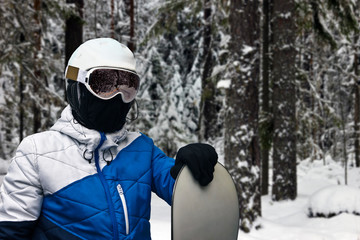 snowboarder with a board in his hand is on the slope of the forest