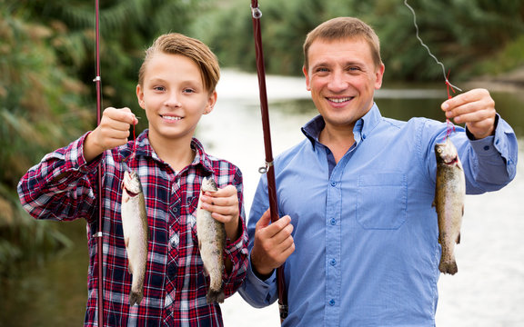 Man with teenager boy showing catch fish