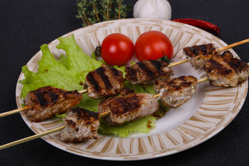 Pork kebab skewers in the plate with salad leaves and tomatoes