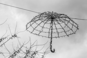 A decorative LED umbrella lamp on the gray sky background. Black and white photo
