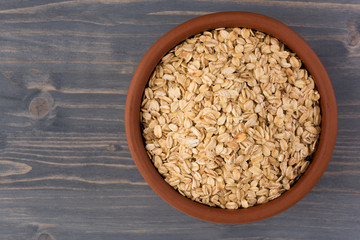 Rolled oats or oat flakes in bowl on wooden background. Healthy lifestyle, healthy eating concept. Top view