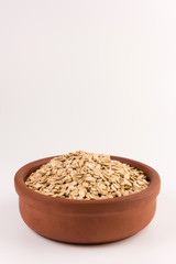 Dry rolled oatmeal in bowl isolated on white background.