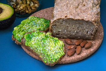 Healthy avocado toasts for breakfast or lunch with rye bread, sliced avocado, arugula, pumpkin and sesame seeds, salt and pepper. Vegetarian sandwiches. Plant-based diet. Whole food concept.