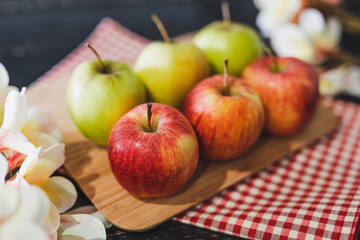 group of apples on wooden cutting board with napkin and flowers