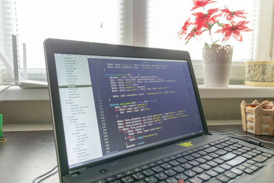 Modern software development background: nice looking laptop with programm on display.