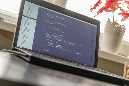 Modern software development background: nice looking laptop with programm on display.