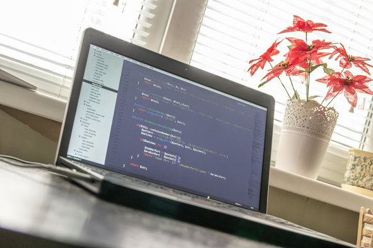 Modern software development background: nice looking laptop with programm on display.