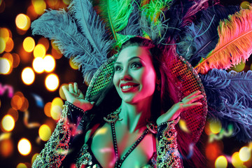 Beautiful young woman in carnival peacock costume. Beauty model woman at party over holiday background with magic glow. Christmas and New Year celebration. Glamour lady with perfect make up and © master1305