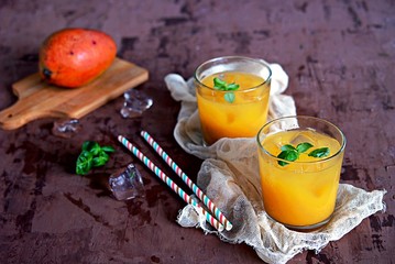 Mango lassi, traditional Indian drink in glasses. Served with ice and straw.