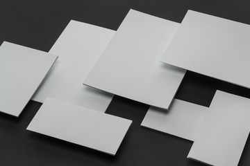 Flat lay with white sheets of paper and cards on black background