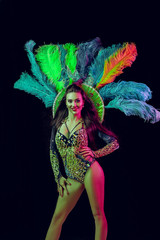 Fototapeta na wymiar Beautiful young woman in carnival peacock costume. Beauty model woman at party over holiday background with magic glow. Christmas and New Year celebration. Glamour lady with perfect make up and