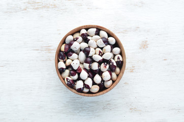 Fototapeta na wymiar Raw beans in a bowl on a white wooden background.