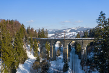 Winter scenery in Silesian Beskids mountains. Railwai viaduct in Wisla Glebce. Aerial view from above. Landscape photo captured with drone. Poland, Europe.